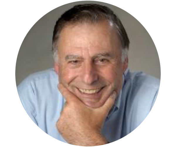 Headshot of G. Stockman. He is smiling and resting his head on his hand. He is light-skinned, has short, mixed black-and-gray hair, and is wearing a light blue shirt.