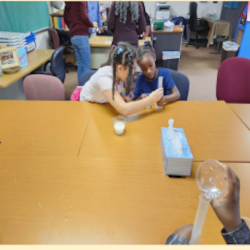 Two young girls working together to make glue