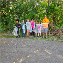Bennie and six Greer students standing in a line at the edge of a parking lot holding trash bags